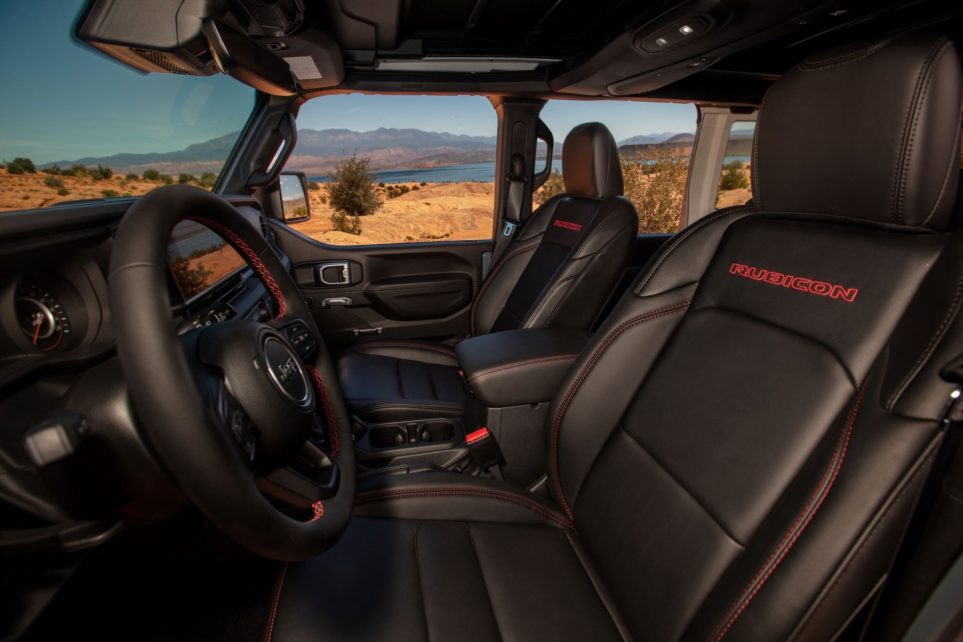 the front interior of a jeep wrangler rubicon with black leather and red stitching with rubicon stitched into the seats.