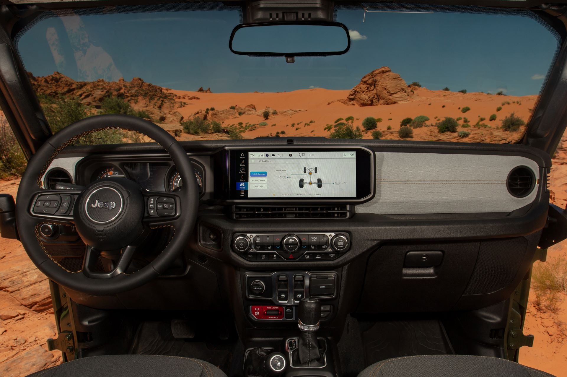 the front infotainment display and digital display of a jeep wrangler with a desert background