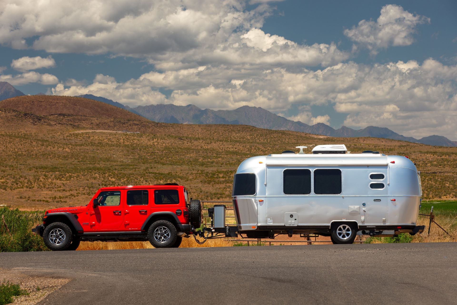 a red jeep wrangler hauling a silver camper