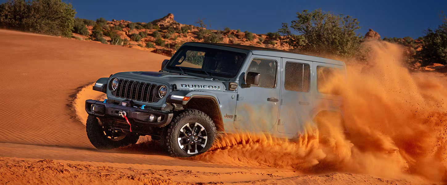 a 2025 jeep wrangler rubicon in anvil driving in the desert with sand