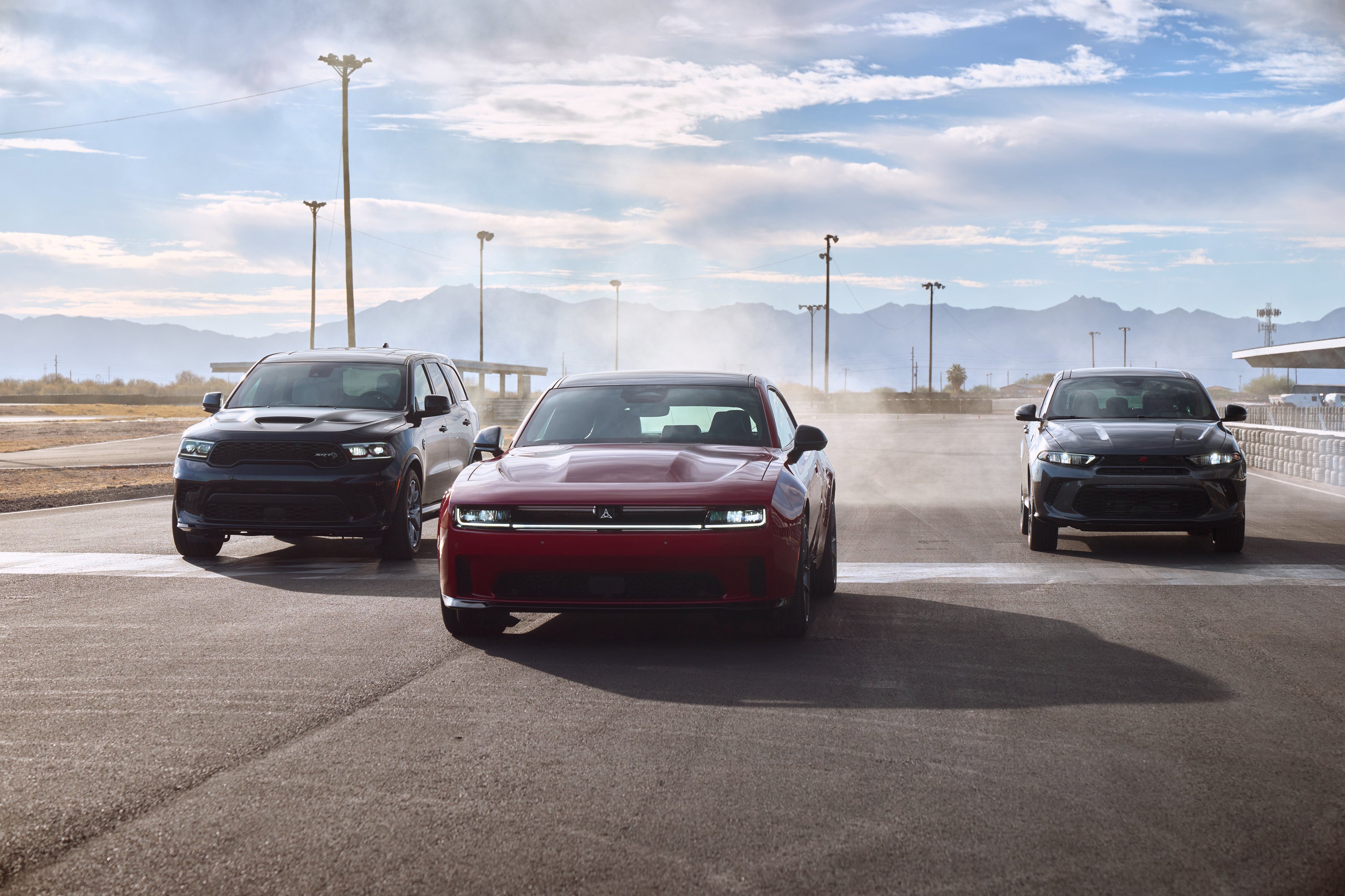 Three dodge chargers lined up next to eachother driving on the road.