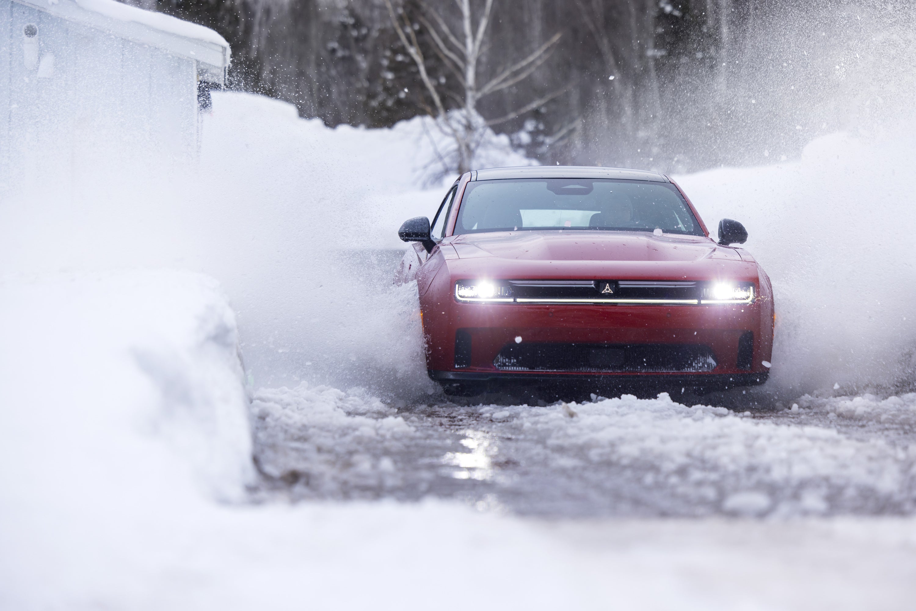 A red charger driving through the snow.