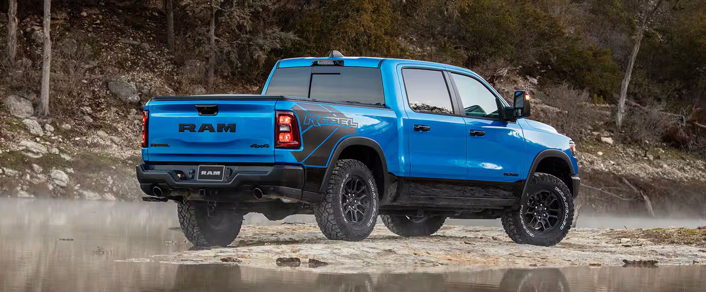 the back view of a blue truck next to water