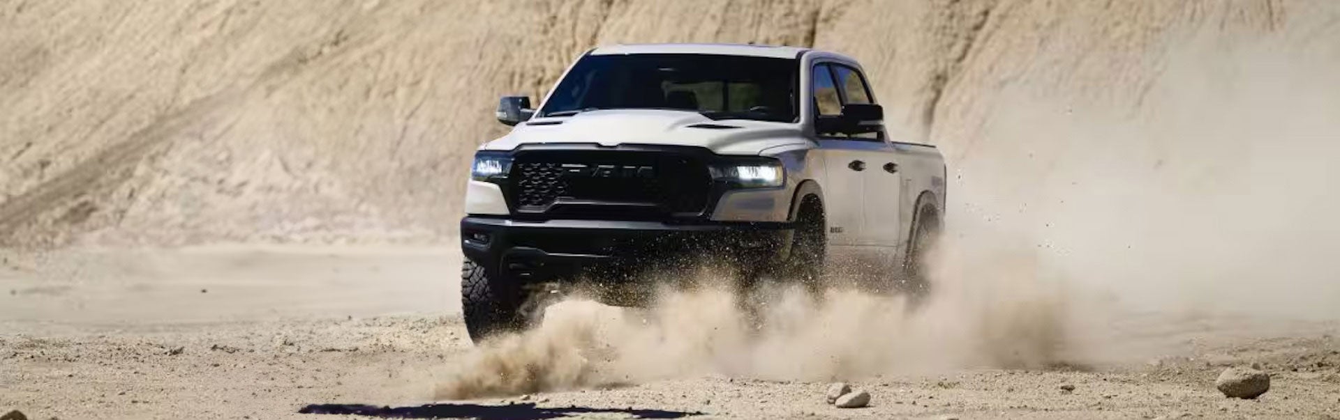 A white Ram 1500 powerslides through a desert valley.